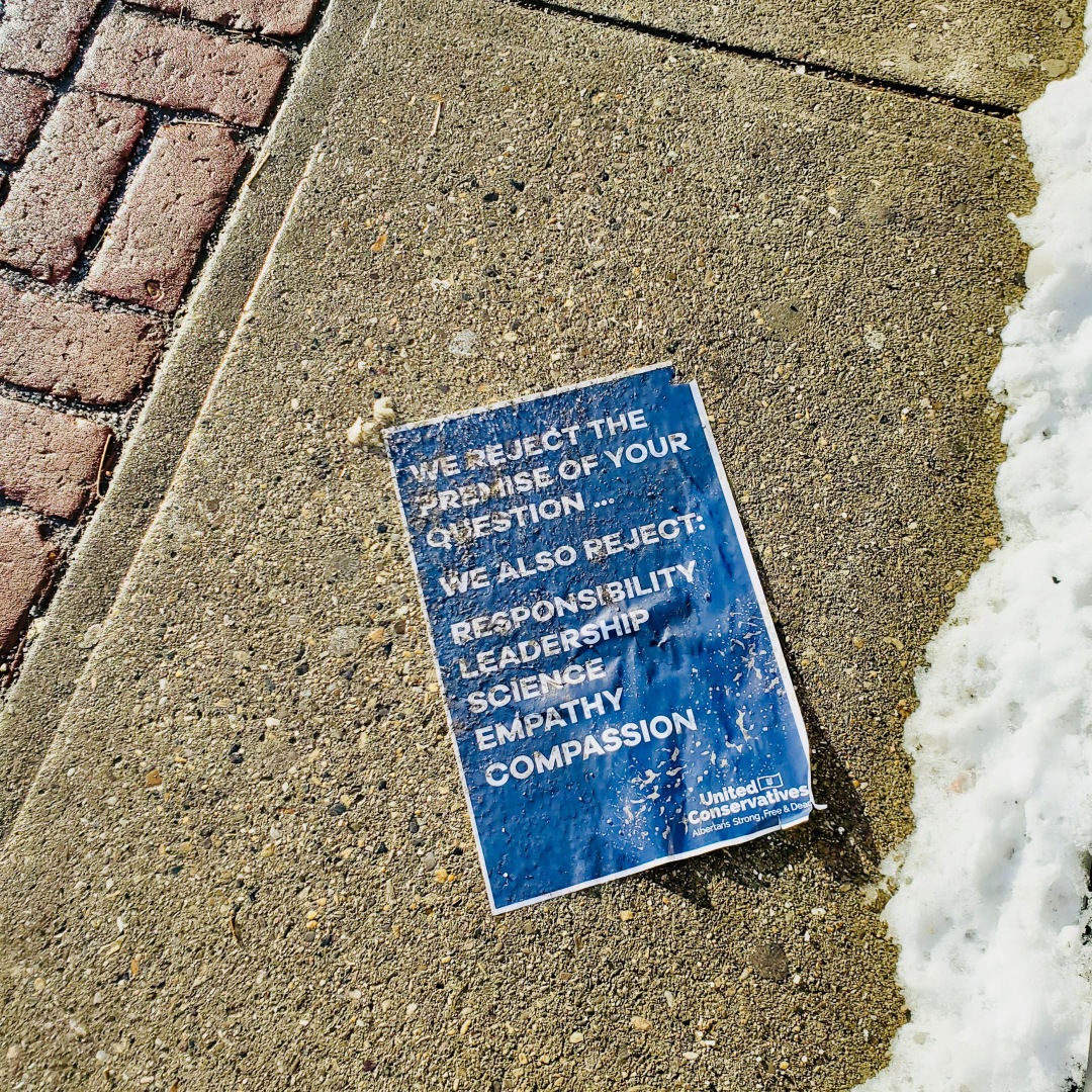 Poster on sidewalk with signs of it being trampled. Sign reads: "We reject the premise of your question...We also reject: Responsibility, Leadership, Science, Empathy, Compassion. The logo at the bottom is United Conservatives, Albertans Strong, Free & Dead